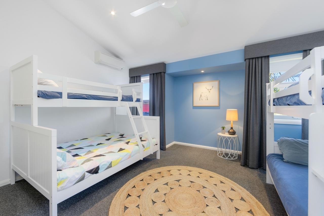 Fourth bedroom with 1st set of bunk beds has a double bed on bottom, single on top. 2nd set of bunk beds have single sized top and bottom. Has split system air con and ceiling fan. upstairs. Laze at Lighthouse