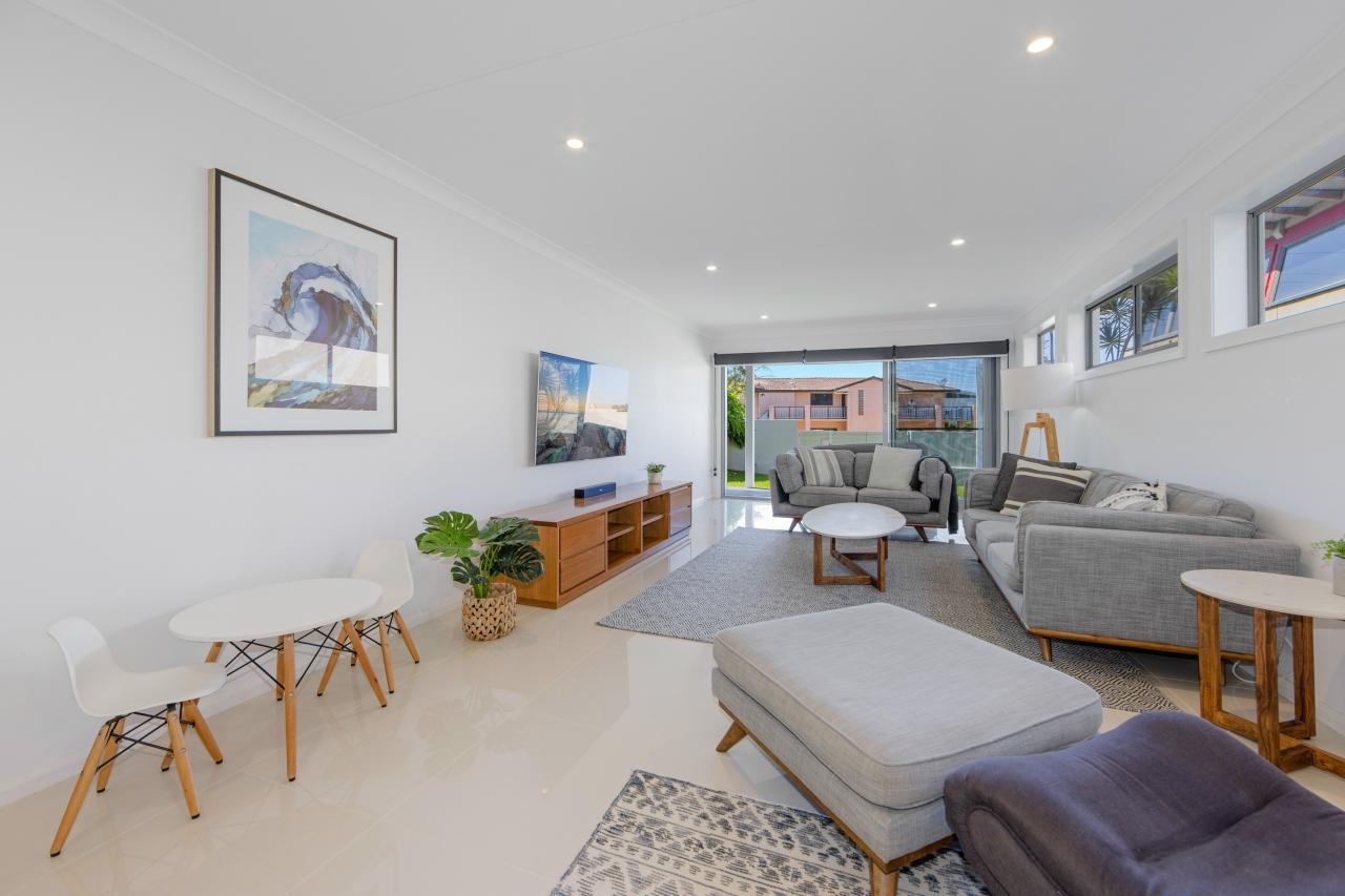 Downstairs open plan living room with smart TV and aircon, leading out to enclosed front yard. Laze at Lighthouse