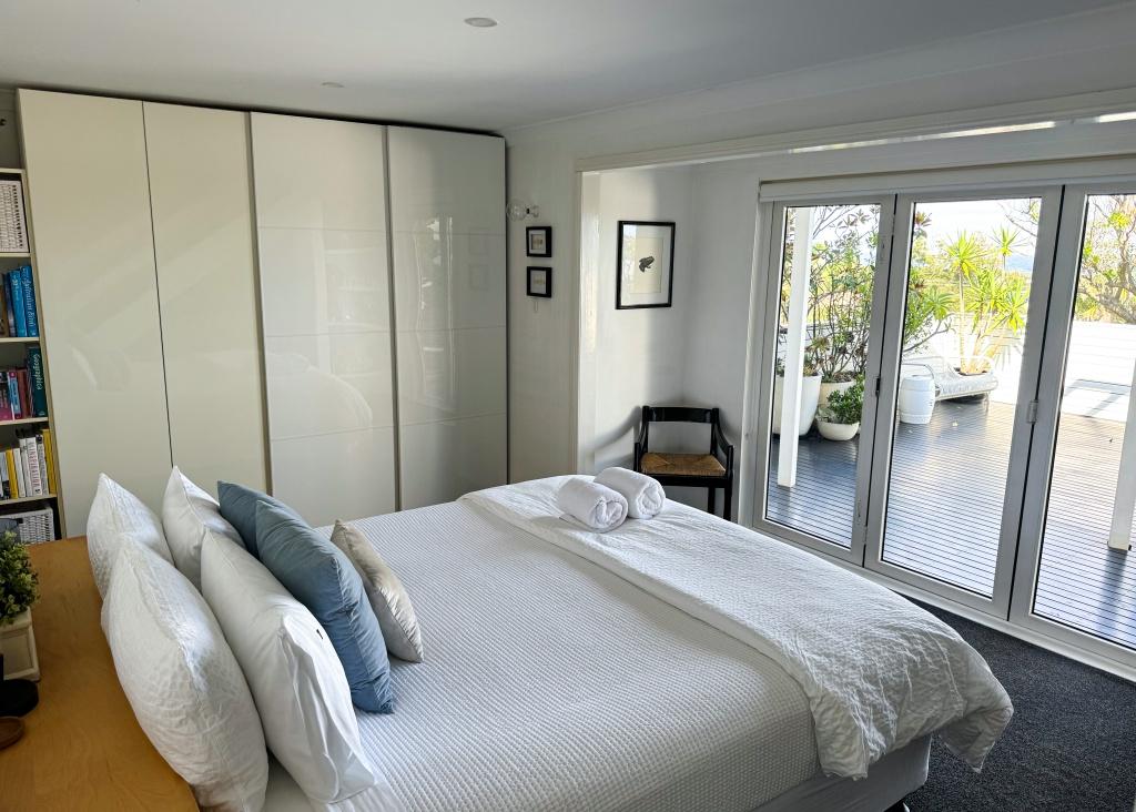 Master bedroom with bi-fold french doors opening directly out onto the lower level balcony with breath taking water views