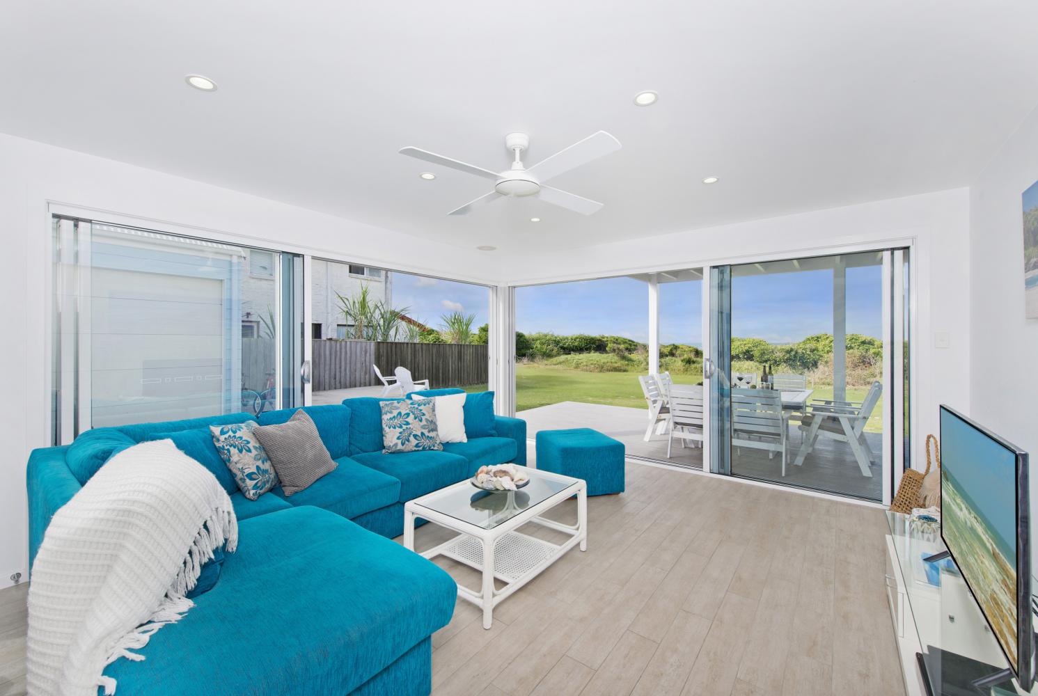 Living room leading to outdoor dining. Has air con and smart TV. Middle Rock Beach House