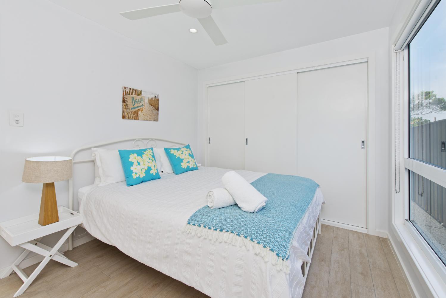 Downstairs bedroom with queen bed and ceiling fan. Middle Rock Beach House